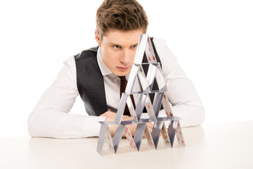 Obraz premium focused man making pyramid from playing cards isolated on white