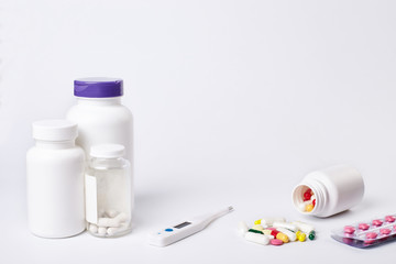 Bottels with drug, pills and thermometer on white background.