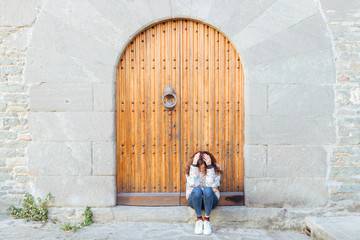 Sad girl sitting on threshold of the closed door Bend down the head on her hands