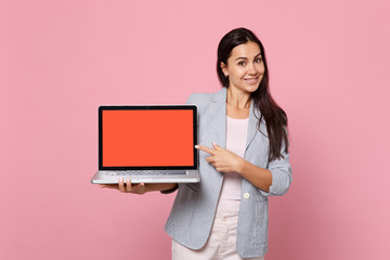 Smiling woman in striped jacket pointing index finger on laptop pc computer with blank empty screen...