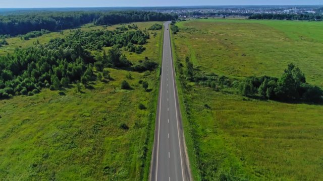 Aerial shot moving forward over countryside highway with moving cars at summer sunny day
