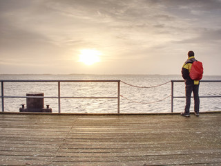 Alone man on pier look over handrail into water