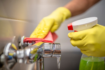 man wiping faucet in kitchen.