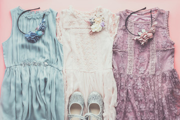 Toned photo of girls' fashion background in pastel colors, lace and tulle dresses, sparkly shoes, flower headbands, flat lay, top view, selective focus