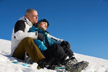 Fototapeta na wymiar young couple resting on a snowy mountain after skiing