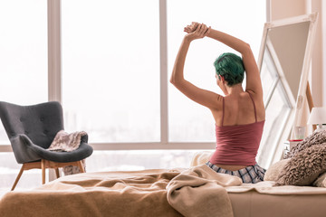 Green-haired woman in pajamas waking up in the morning