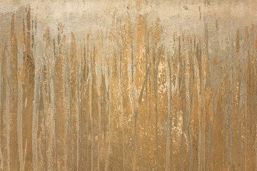 old yellow concrete wall with scratches and gray vertical streams of paint. rough surface texture