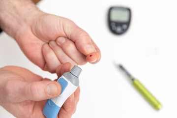 Diabetic is doing a glucose level finger blood test