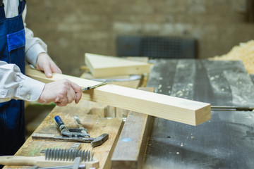 Wood processing. Confident young male carpenter working with wood in his workshop