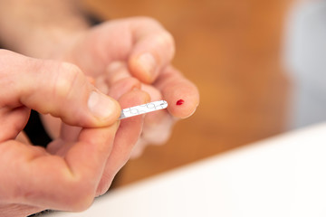 Diabetic is doing a glucose level finger blood test