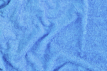 Dark blue crumpled textiles are unevenly laid out. The texture of a terry towel. Blank background.