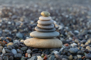 Fototapeta na wymiar Stones pyramid on pebble beach symbolizing stability, zen, harmony, balance. Shallow depth of field.