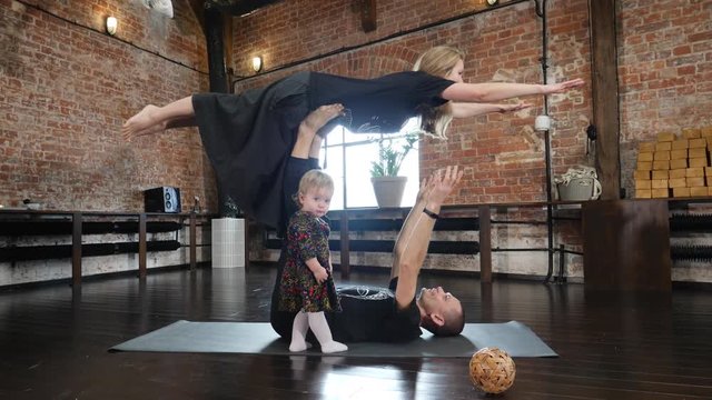 Acro yoga studio family father practice a pose with mother and baby daughter