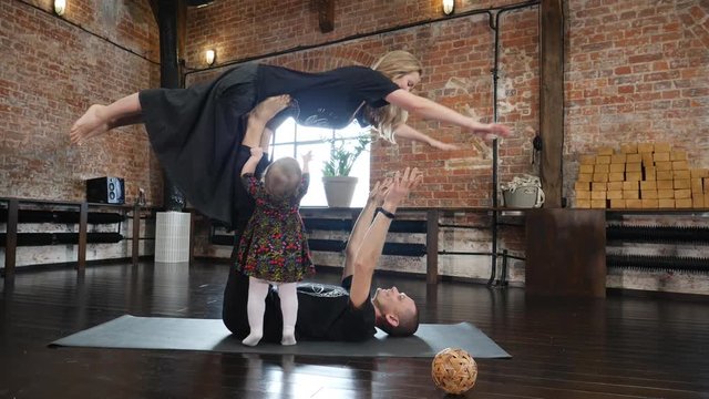 Acro yoga studio family father practice a pose with mother and baby daughter