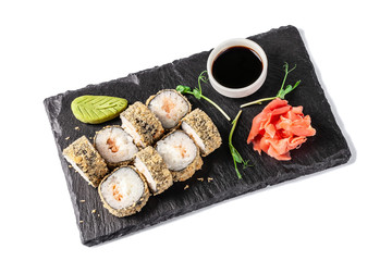 Concept of Japanese cuisine. Deep fried roll with salmon and mayonnaise in Panko bread crumbs. Near soy sauce, ginger and wasabi. Modern serving dishes in the restaurant on a black slate blackboard.