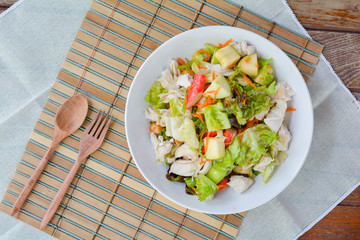 Healthy food for loose weight high fiber and vitamins. Chicken breast salad (Green apple, carrot, vegetables) in white bowl on wooden table served in dinner. 