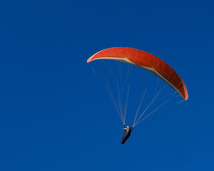 A paraglider is flying over the sea on a beautiful day.