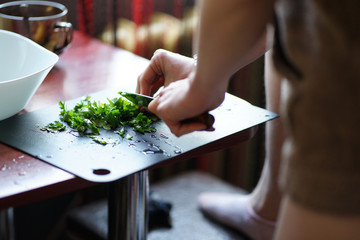 Obraz na płótnie Canvas Woman cutting parsley preparing side dish