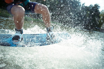 the guy slides on the water.Spray around.Blurred background