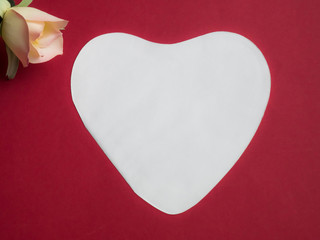 Fototapeta premium White heart with copy space and a rose on red background