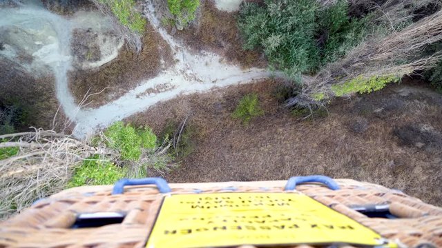 Looking down at ground from basket of hot air balloon. High up flying on a tourist attraction of Cappadocia, Turkey. Scared of falling and acrophobic in precarious position.