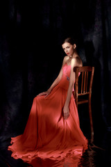 Beautiful woman in red evening dress on dark background