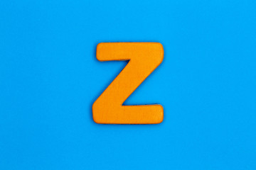 Wooden letter z painted orange on a blue background