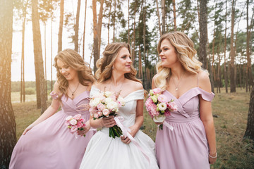 Wedding bouquet in hands. Beautiful bride with her pretty bridesmaids.