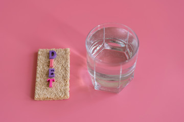 crunchy loaves of bread and a glass of water and the inscription deet on a pink background. Concept of losing weight and healthy lifestyle