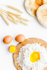 Make bread concept. Flat bread near wheat ears, flour and eggs on white background top view