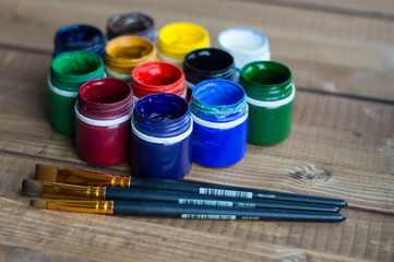 Plastic cans of paint and gouache. Art tools. The art and craft. Closeup. Wooden background.