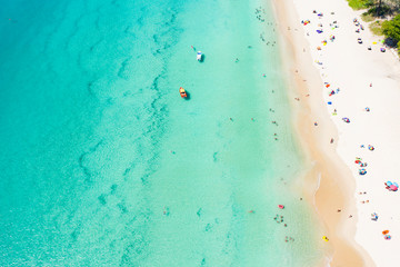 Fototapeta na wymiar View from above, aerial view of a beautiful tropical beach with white sand, turquoise clear water and people sunbathing, Surin beach, Phuket, Thailand.