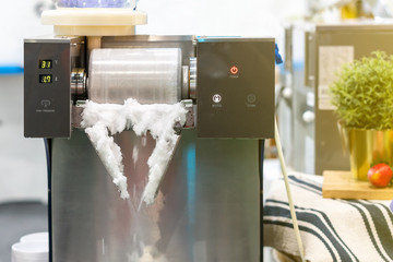 Close up ice flake or snowflake during making from modern and automatic bingsu machine (asian or korean dessert)