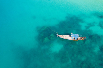 View from above, stunning aerial view of a traditional long-tail boat floating on a turquoise and clear sea. Tropical beach with white sand, Freedom beach, Phuket, Thailand.