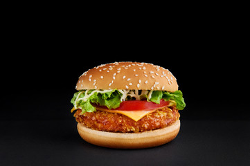 burger with cutlet, cheese, tomato, lettuce isolated at black background