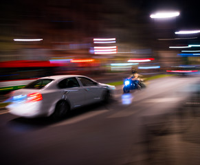 Fototapeta na wymiar Dangerous city traffic situation with a motorcyclist and a car in motion blur