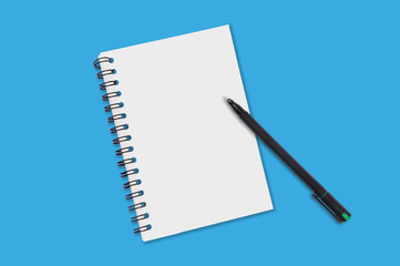 One paper notepad with spiral binder and blank sheets near black plastic pen lies of blue office table. Top view. Copy space for your text. Concept of business or education