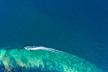View from above, aerial view of a traditional long-tail boat sailing near a stunning barrier reef...