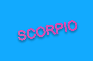 Word scorpio cut out of purple paper on blue table. Top view. Horoscope concept