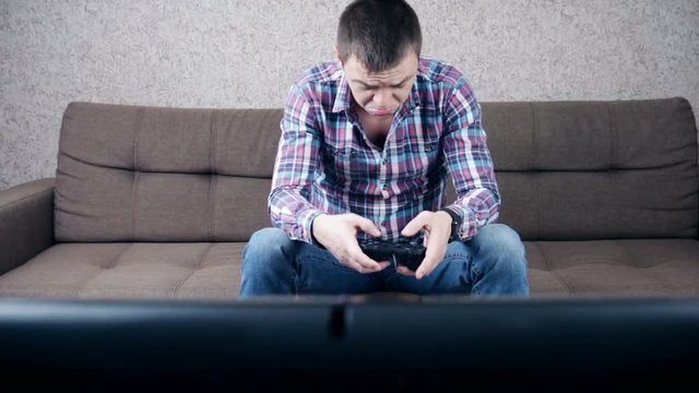 Stressed depressed young man playing gaming on pad