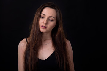 Fototapeta premium Sad brunette women on a dark background. Depression, negative emotions.