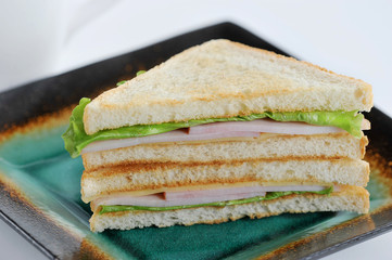 ham, cheese and lettuce sandwich on a green plate