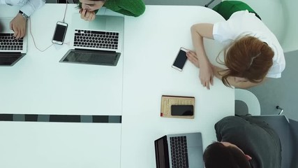 Top view of a modern office with specialists team at work with laptops and smartphones, modern technologies concept. Office workers sitting and discussing ideas, view from above.