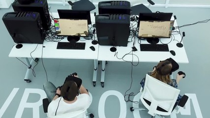 Top view of a modern office with testing games specialists in virtual reality glasses, modern technologies concept. Man and woman in VR glasses playing games.