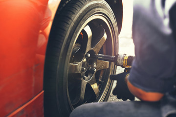 auto mechanic fastens car wheel