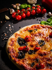 Traditional Italian pizza, vegetables, ingredients on a dark background. Pizza is cooking in the oven. Pizza menu.