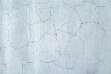 Gray concrete wall covered cracked plaster. Cracks on the wall resemble a map of the world with the borders of States
