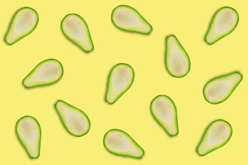 Lots of scattered tasty fresh halves of organic avocado on yellow table in kitchen or market. Top view. Cooking concept. Seamless pattern
