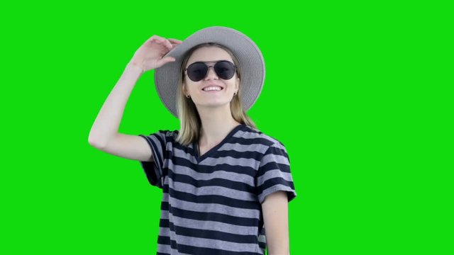 Young funny hipster girl in hat having fun and dancing over green background. Chroma key