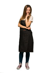 Full body Young woman with apron looking down with the hand on the chin on isolated background